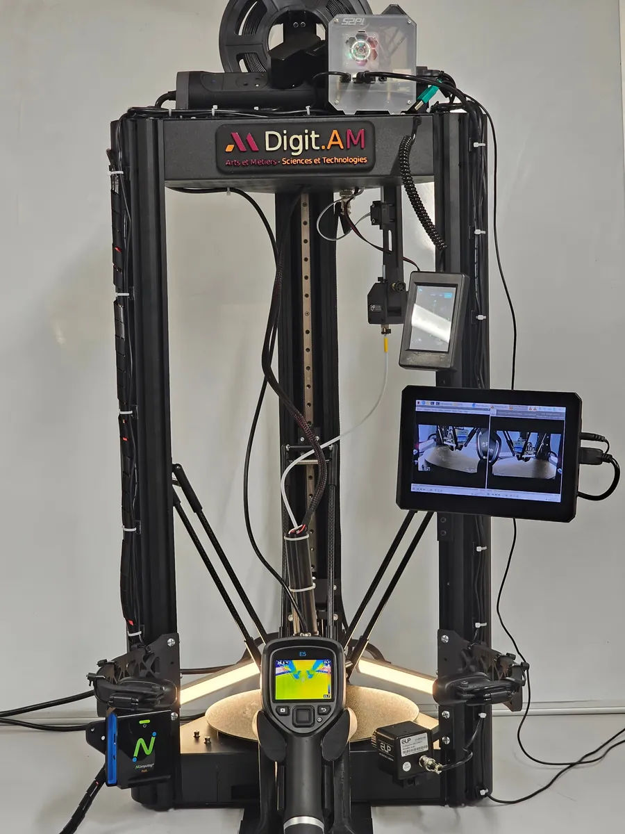 Front view of the Digit.AM delta printer: control screen with two live camera views, a thermal camera, cameras on side arms and a sensor on the effector.